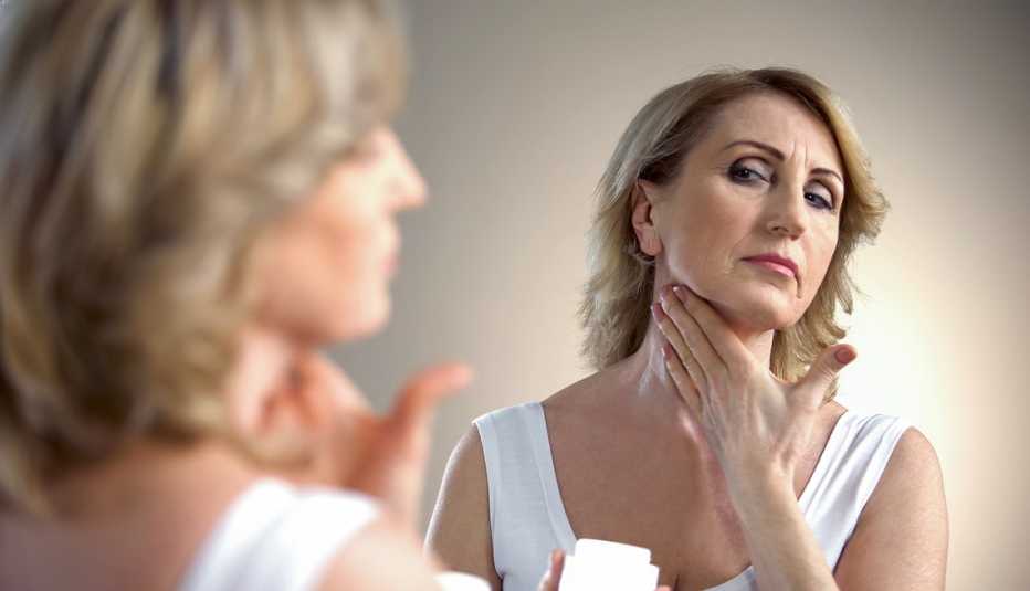 A woman applying cream on her neck