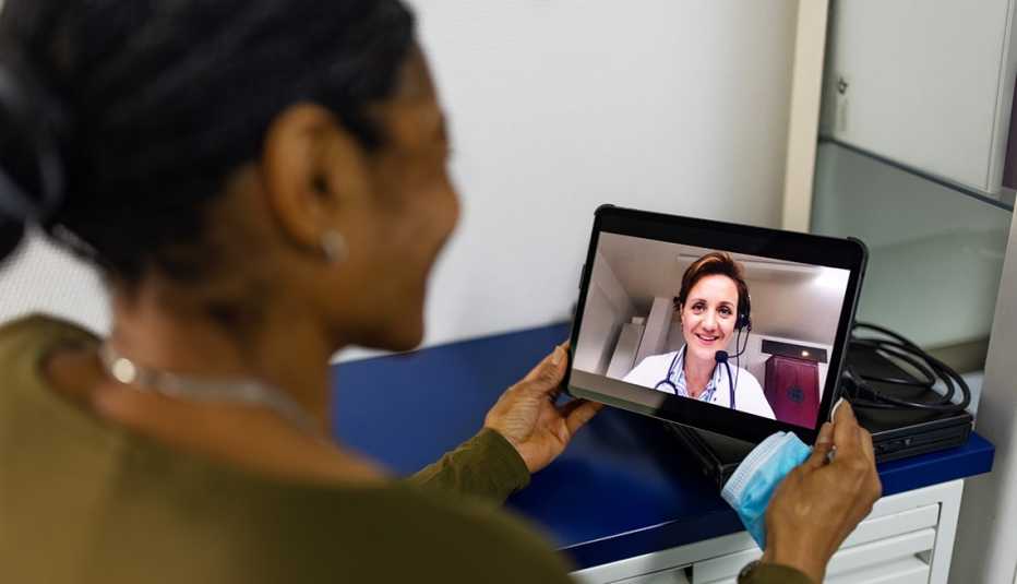 A woman using a tablet to have a telehealth video conferencing appointment with a doctor