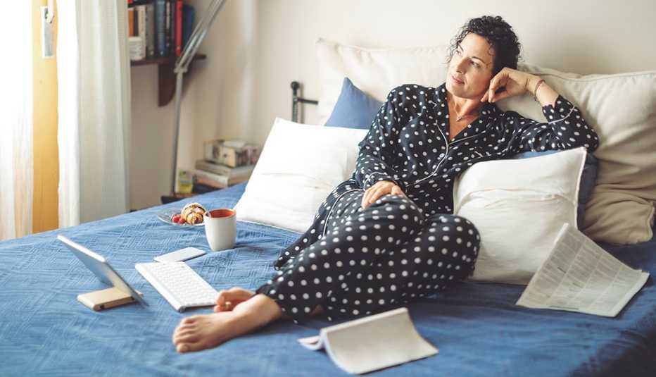 A woman in black and white polka dot pajamas lying in bed