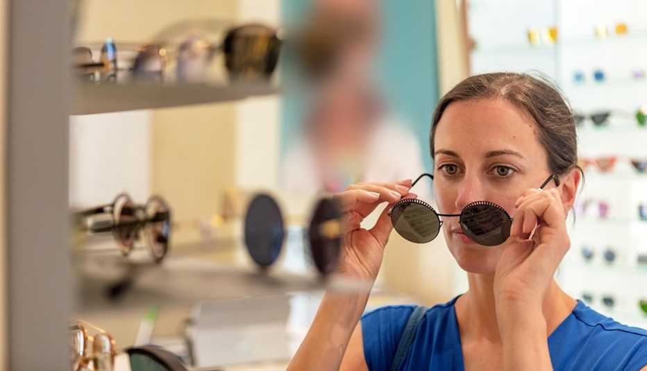 A woman looking at a mirror in a store trying on sunglasses