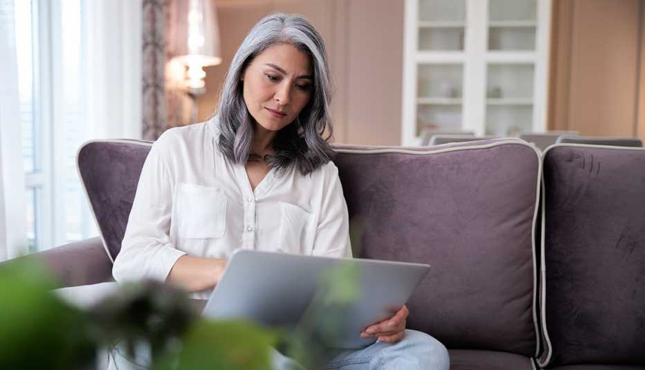 A woman sitting on a sofa using a laptop