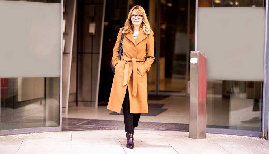 A woman walking out of a building wearing a beige trench coat