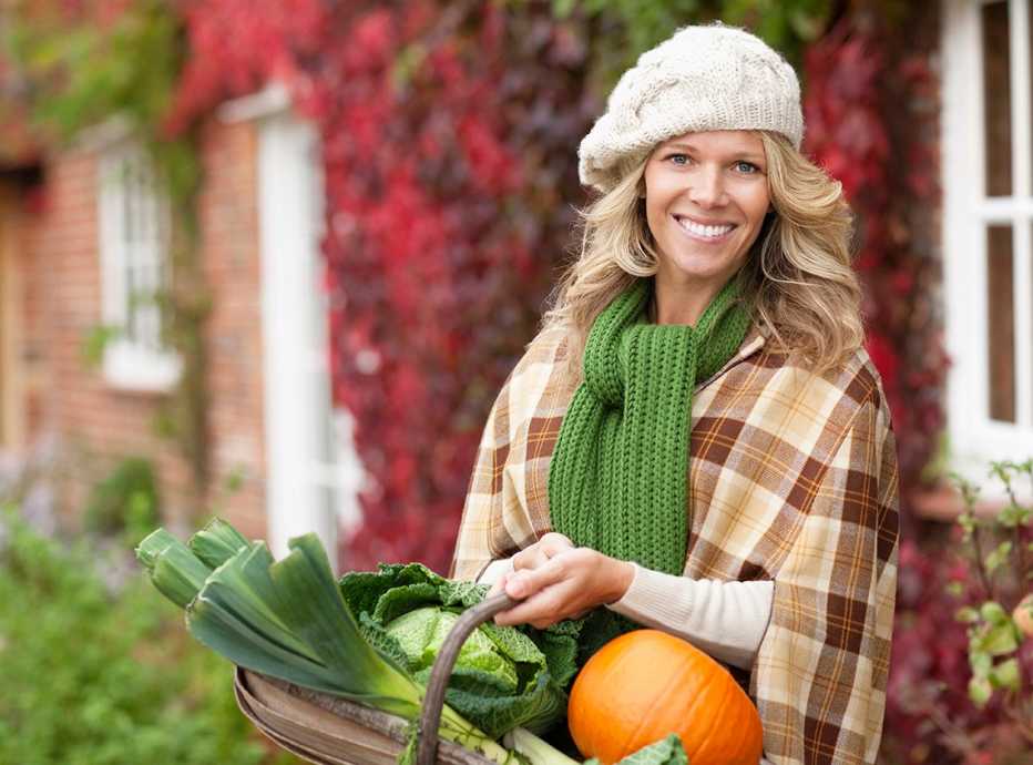 A woman holding a basket of vegetables and a pumpkin
