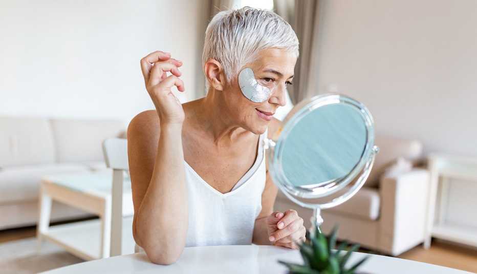 A woman wearing an eye mask looks into a vanity mirror