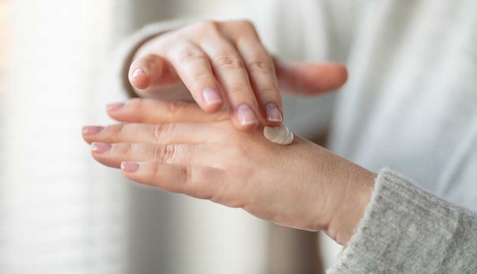 A closeup of a woman applying hand cream