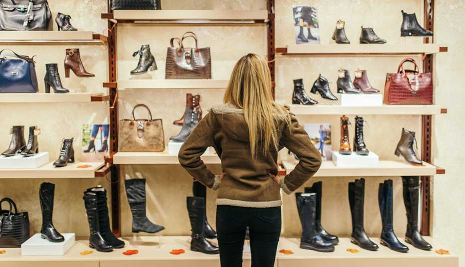 a woman looking at a display of boots and purses while shopping in a store