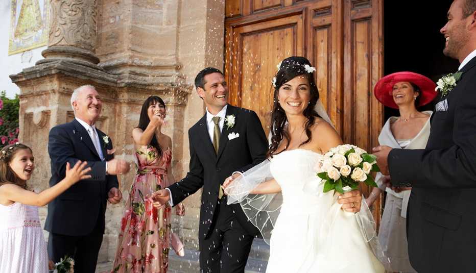 wedding guests throwing confetti over bride and groom on church steps