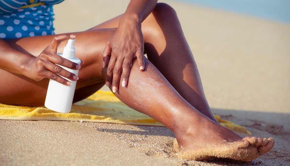A close up of a woman applying sunscreen on her legs