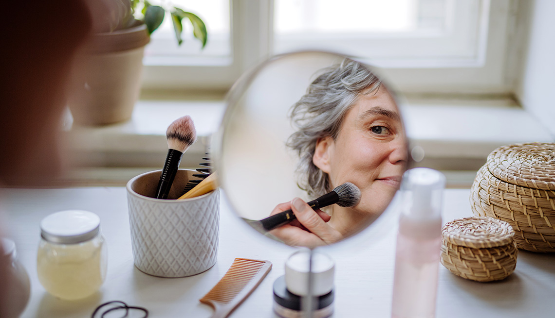A woman applying makeup in front of a mirror on a table