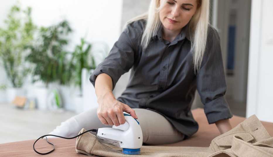 A woman using a fabric shaver on her trousers