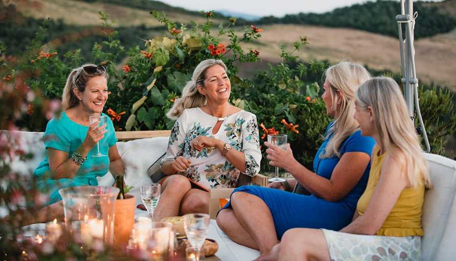 Four women sitting outside drinking wine while talking to each other