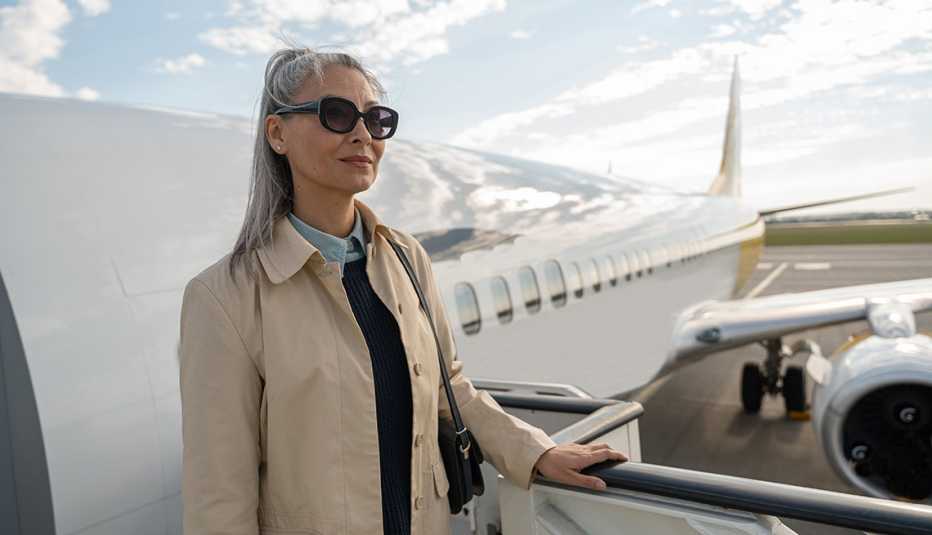 a female passenger in sunglasses standing on the steps outside of the door of a plane