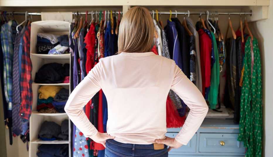 a woman with her hands on her hips looking into her closet