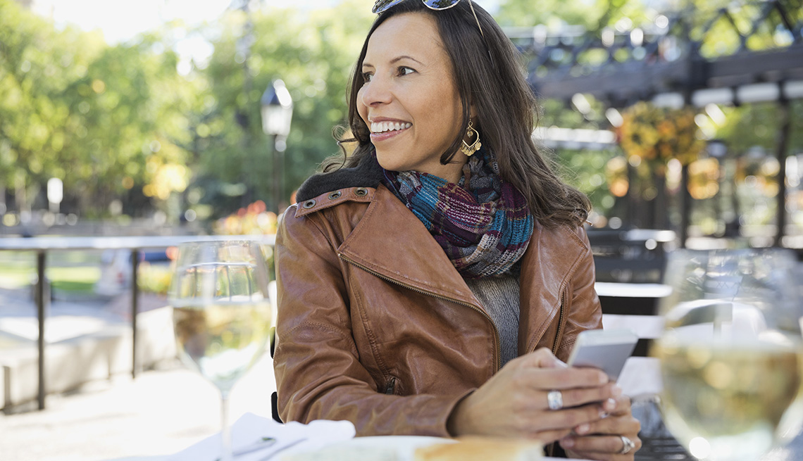A woman wearing a brown leather jacket sitting at table at an outdoor restaurant