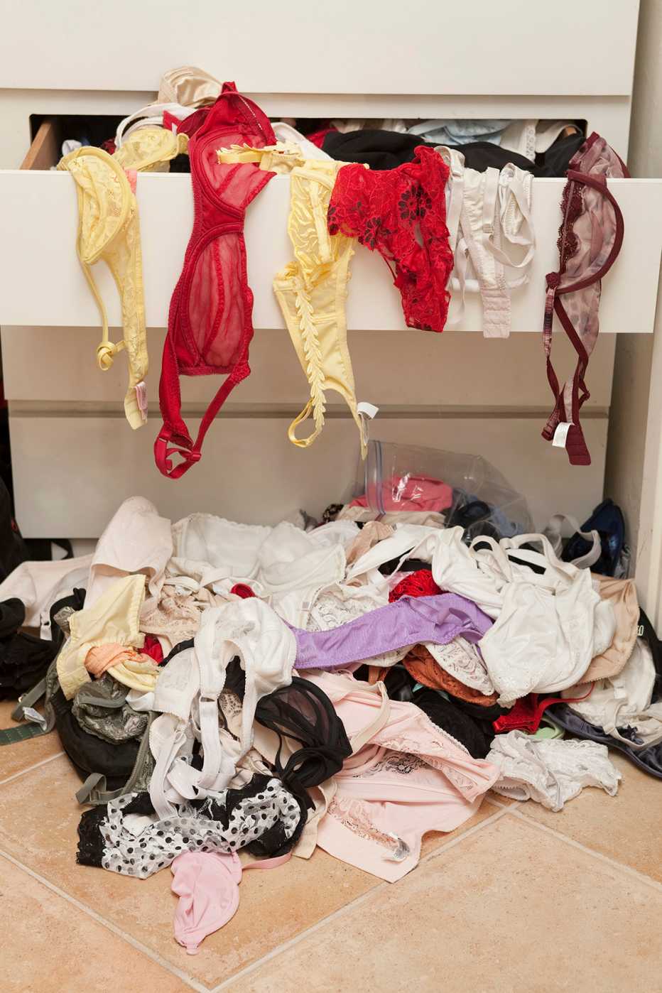 disorganized women's underwear piled on a floor and in a dresser drawer