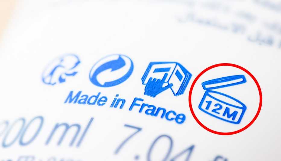 A closeup of a bottle's manufacturing label that shows it was Made in France and has a 12 month period after opening symbol on it circled in red