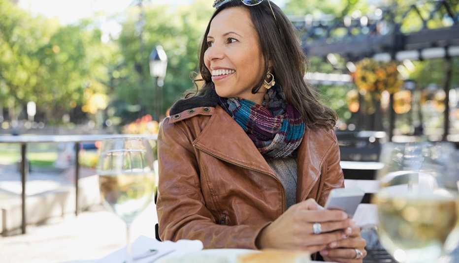 A woman wearing a brown leather jacket sitting at table at an outdoor restaurant