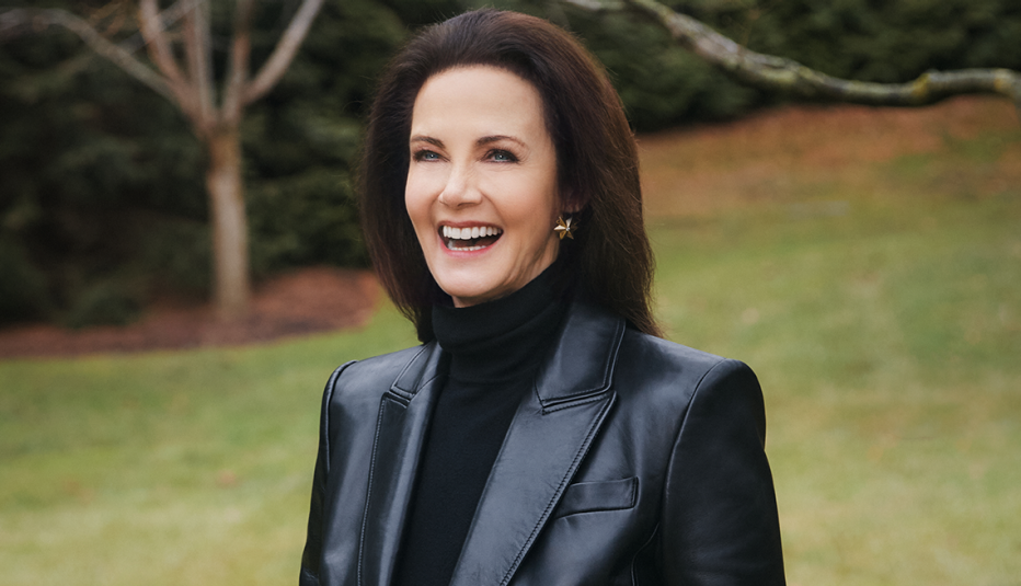 lynda carter smiling outside; grass, shrubs and tree behind her