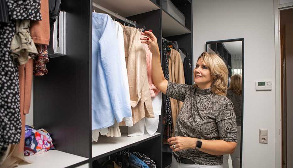 A woman reaching for a shirt inside her walk in closet at home