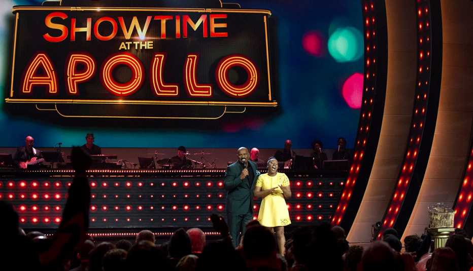 steve harvey on stage with young woman in yellow dress