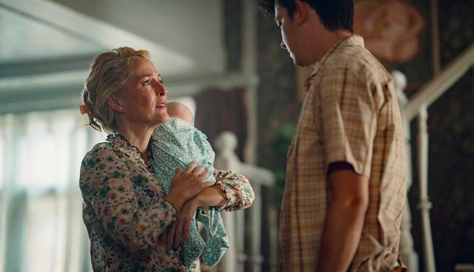 gillian anderson holding a baby next to asa butterfield in a scene from season four in the netflix series sex education