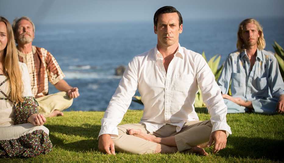 Jon Hamm at the end of a California cliff meditating with other people in a scene from Mad Men