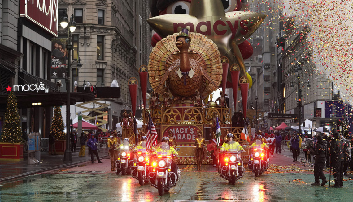 The Tom Turkey float traveling down the street behind a police escort at the Macy's Thanksgiving Day Parade