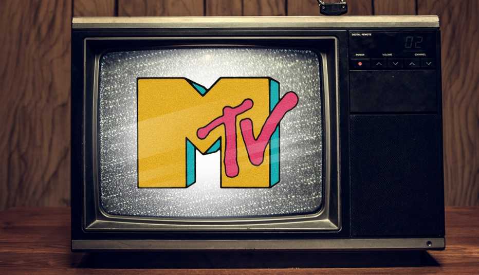 a tv from the eighties on a desk in a wood paneled room with static on the screen and the original m t v logo