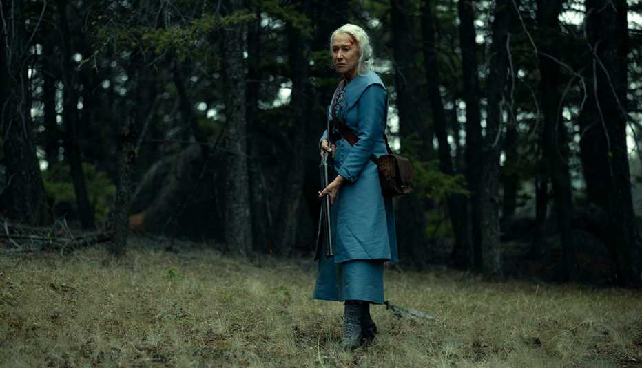 Helen Mirren holding a shotgun in a wooded area in the television series 1923