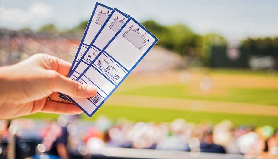Hand holding three tickets while in the stands at a baseball game