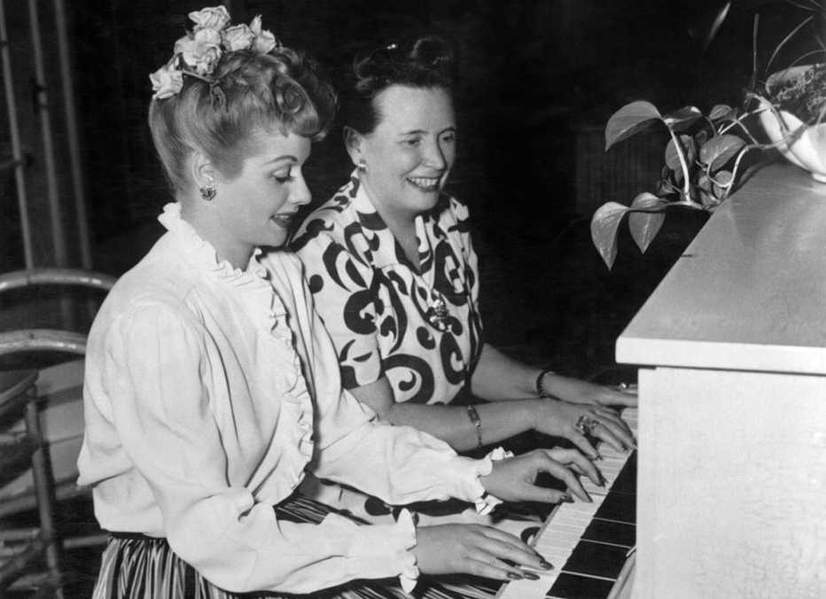 Lucille Ball sitting next to her mother as they both play the piano together