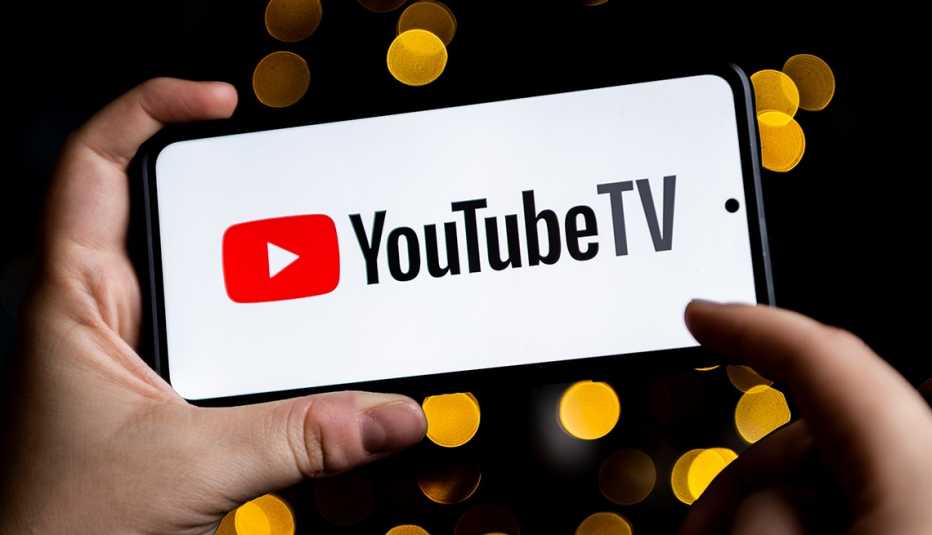a youtube tv logo displayed on a smartphone held in a person's hands