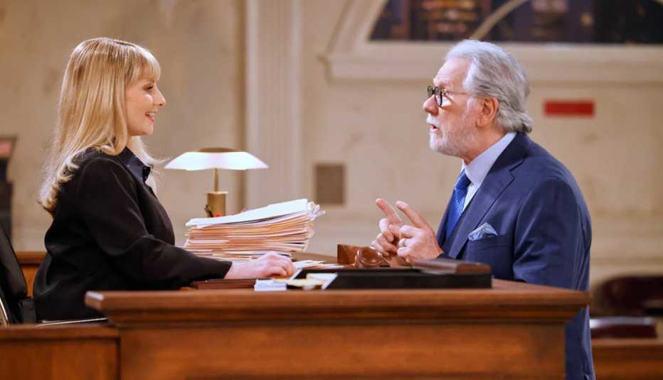 Melissa Rauch and John Larroquette talking to each other in the courtroom in Night Court