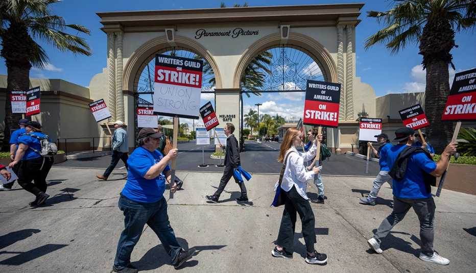 People carrying Writers Guild of America on Strike signs as they picket outside of the studios of Paramount Pictures