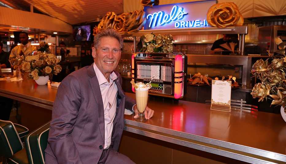 the golden bachelor gerry turner sits at the bar of mel's drive in with a milkshake