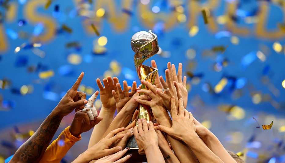 hands reaching up to hold a trophy