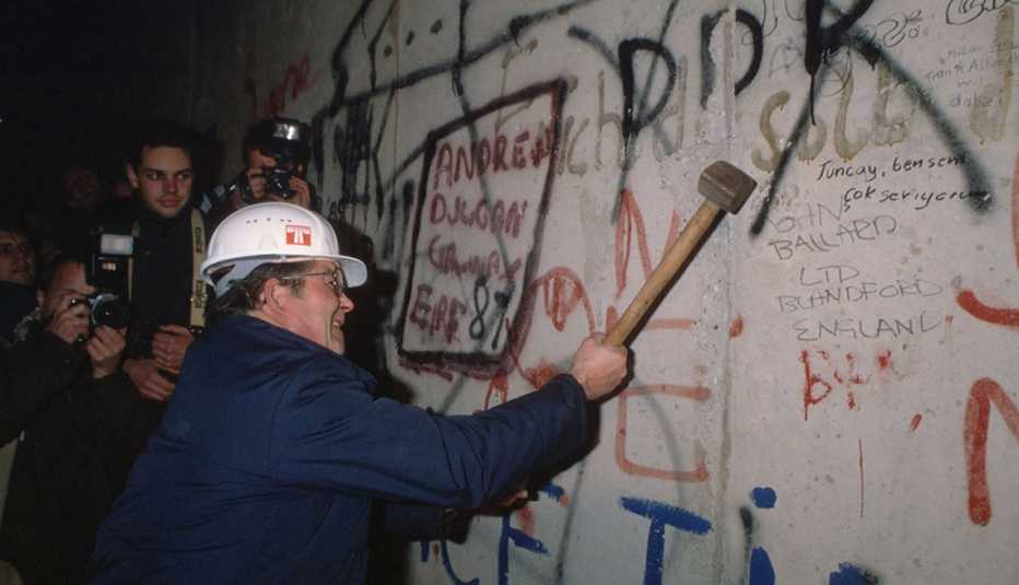 a man knocking a piece of stone from the berlin wall after the opening of the border on november ninth nineteen eighty nine