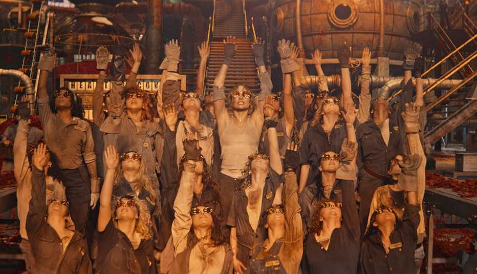 Jennifer Lopez and other dancers with their arms in the air in a steampunk factory in "This Is Me ... Now."
