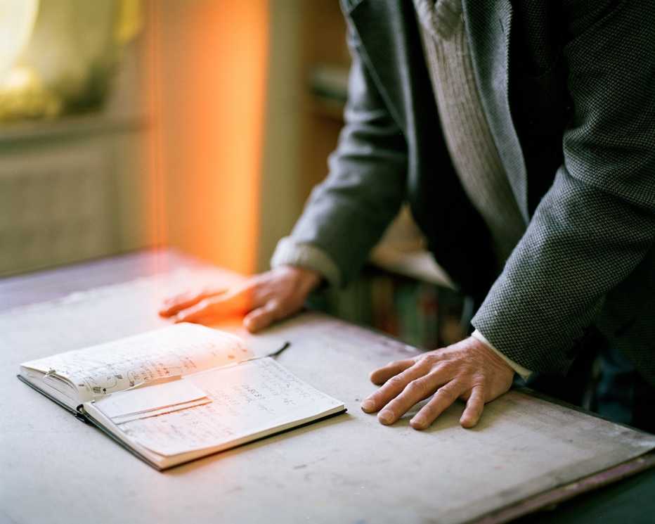 man's hands on desk leaning over a diary