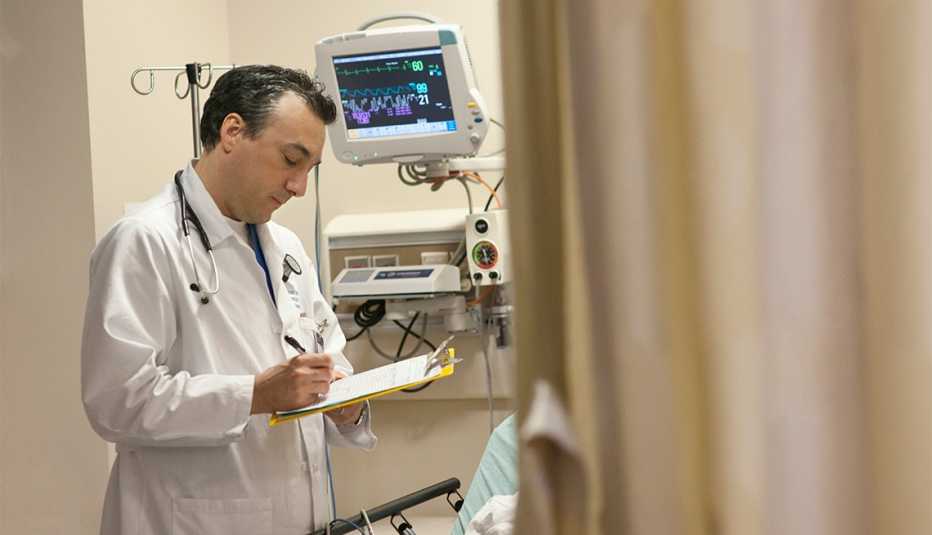 physician writing on clipboard in hospital room