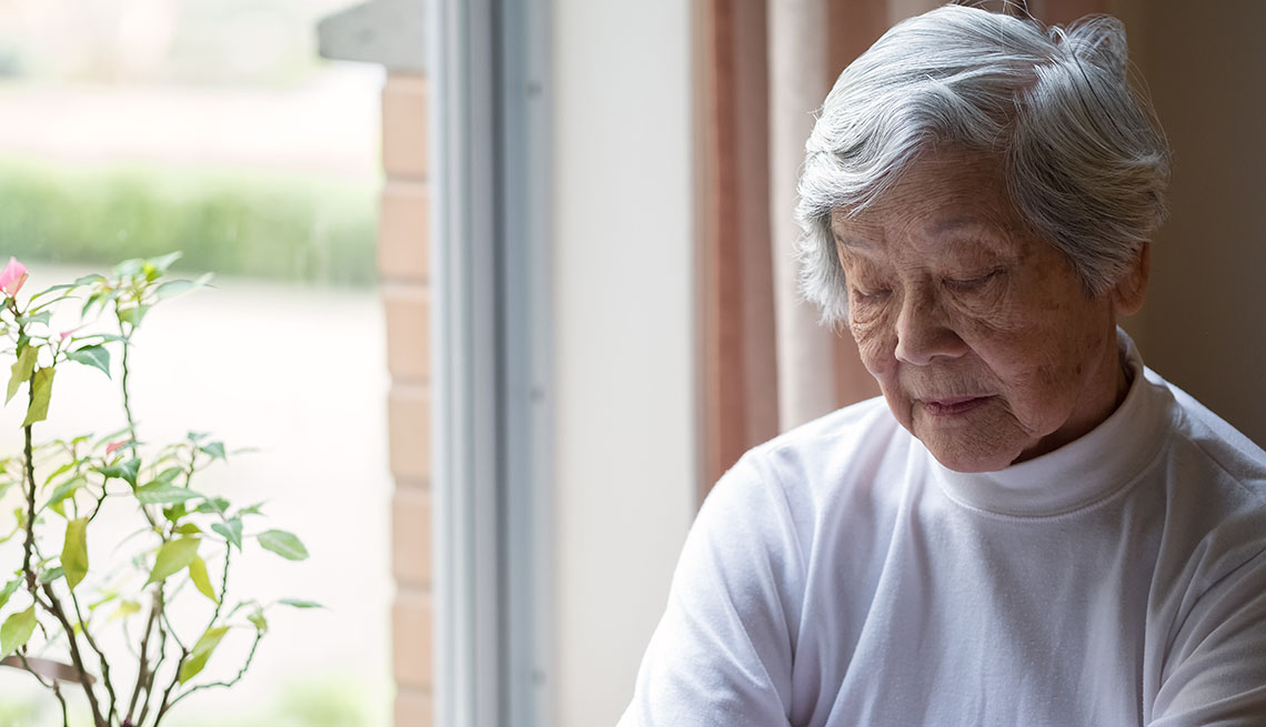 older woman sitting by window with eyes closed