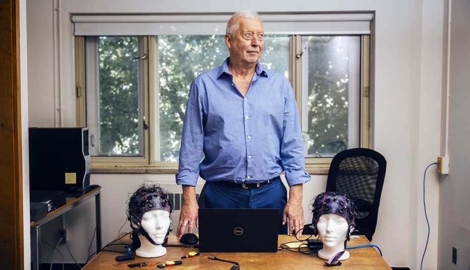 michel thaut in an office with two brain testing caps on mannequin heads on his desk