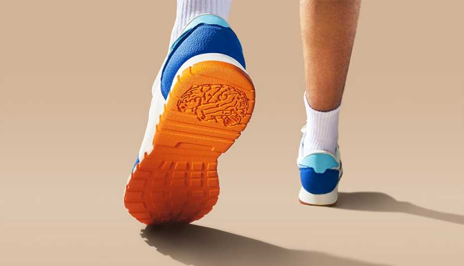 closeup from below and behind a person walking wearing sneakers so the bottom of one sneaker is showing