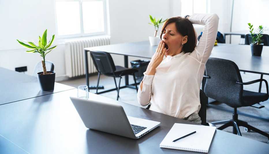 Mature woman yawning at her desk during daytime