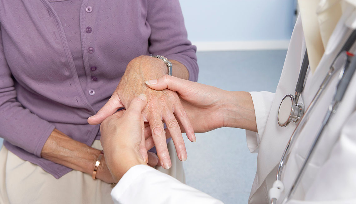 Rheumatoid arthritis. General practitioner examining a patient's hand for signs of rheumatoid arthritis.