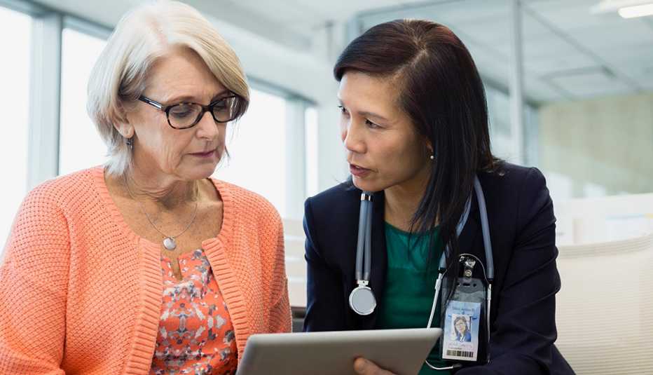 Doctor and mature patient talking and looking at a digital tablet.
