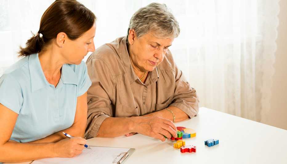Senior woman with puzzle. Medical professional observing her.