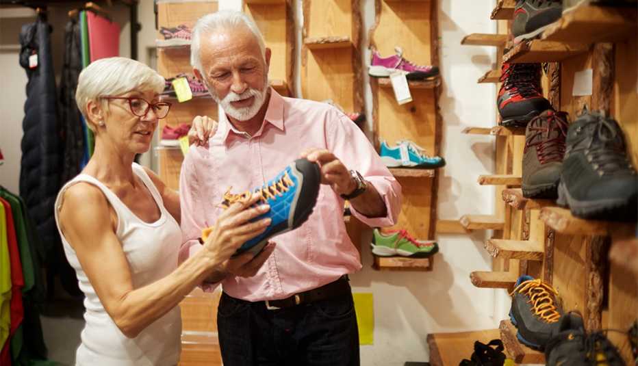 Senior couple in sports and outdoor equipment store choosing hiking shoes.