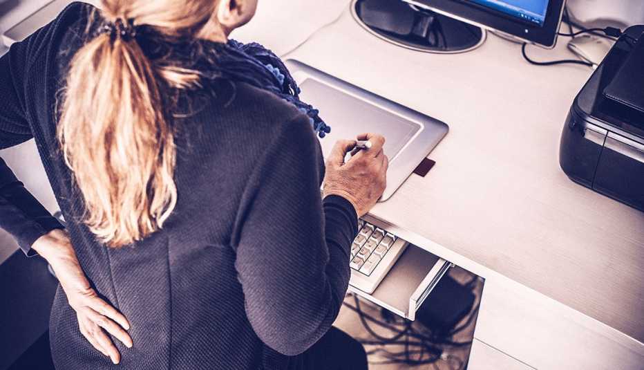 woman with a hand on her lower back in an office setting