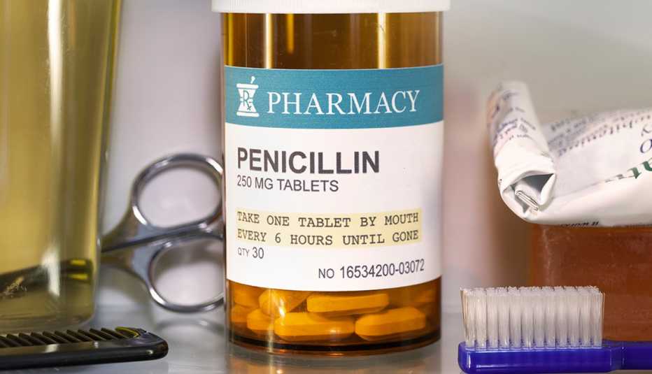 A pill bottle with a Penicillin label sitting in a medicine cabinet with a toothbrush and other toiletries.